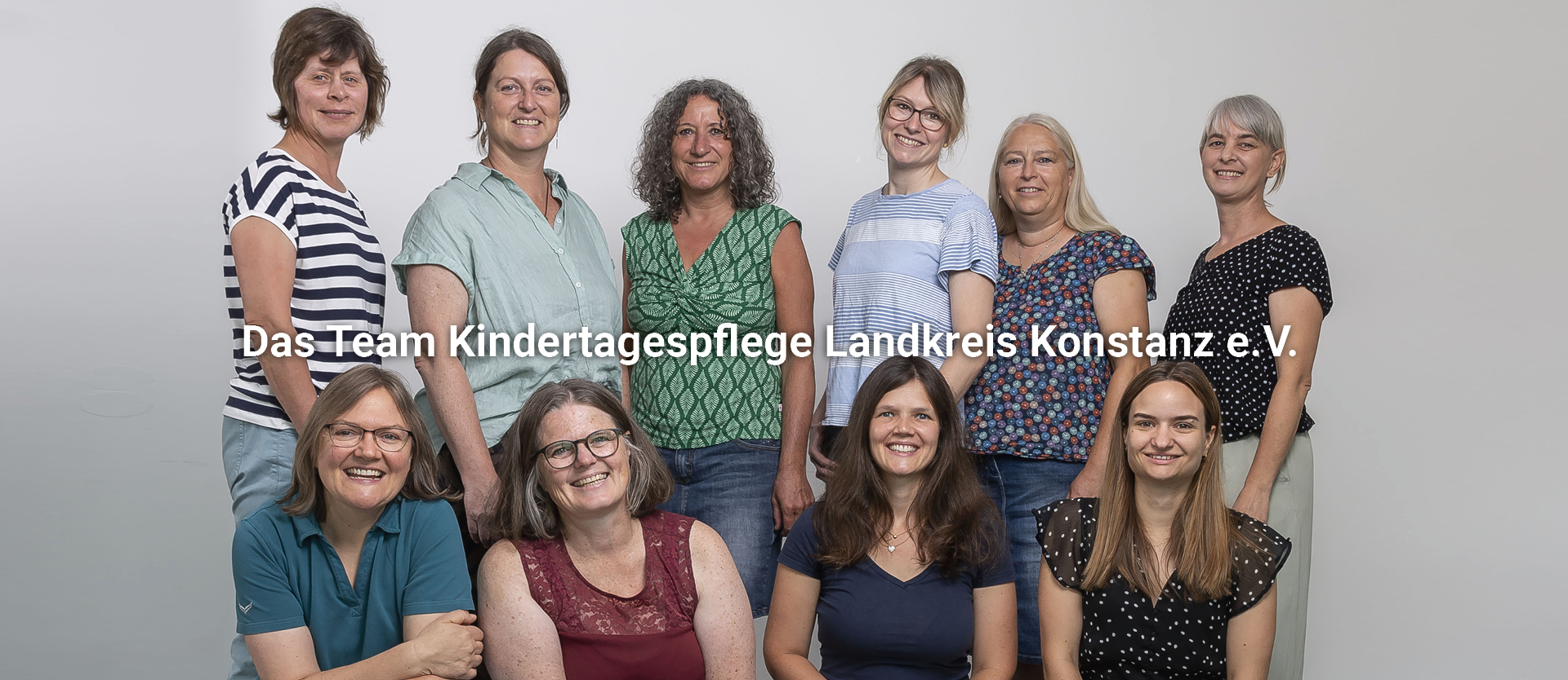 Erwachsene Frauen sitzen in einer Stuhlreihe, eine Frau hält eine rote Feder in der Hand und spricht.